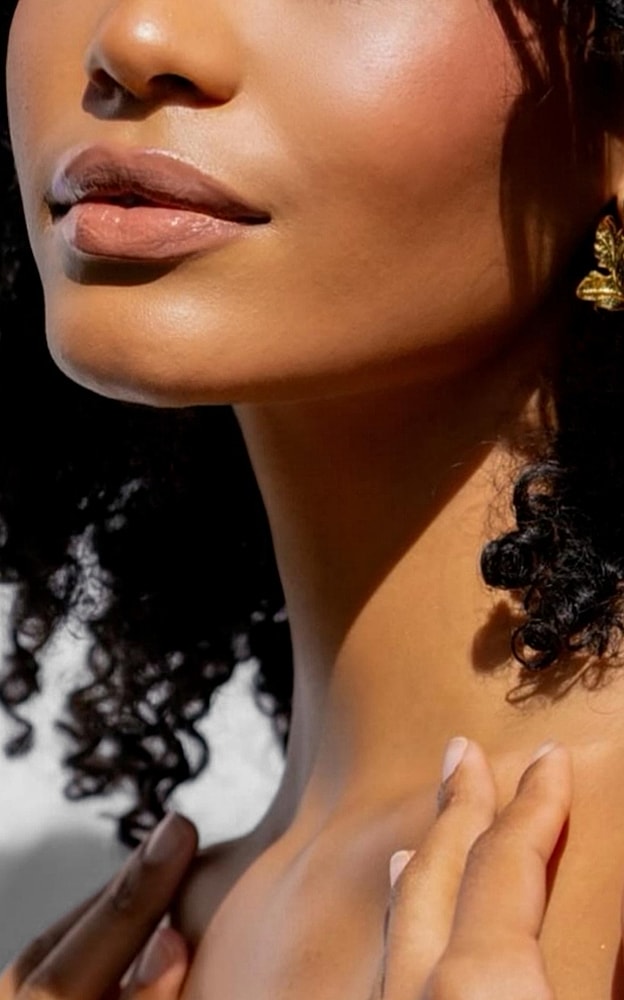 Close-up of woman with curly hair and earrings.
