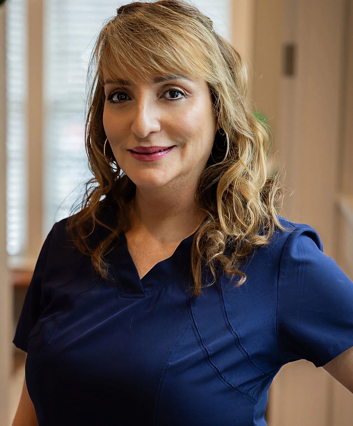 Female in blue medical scrubs smiling indoors.