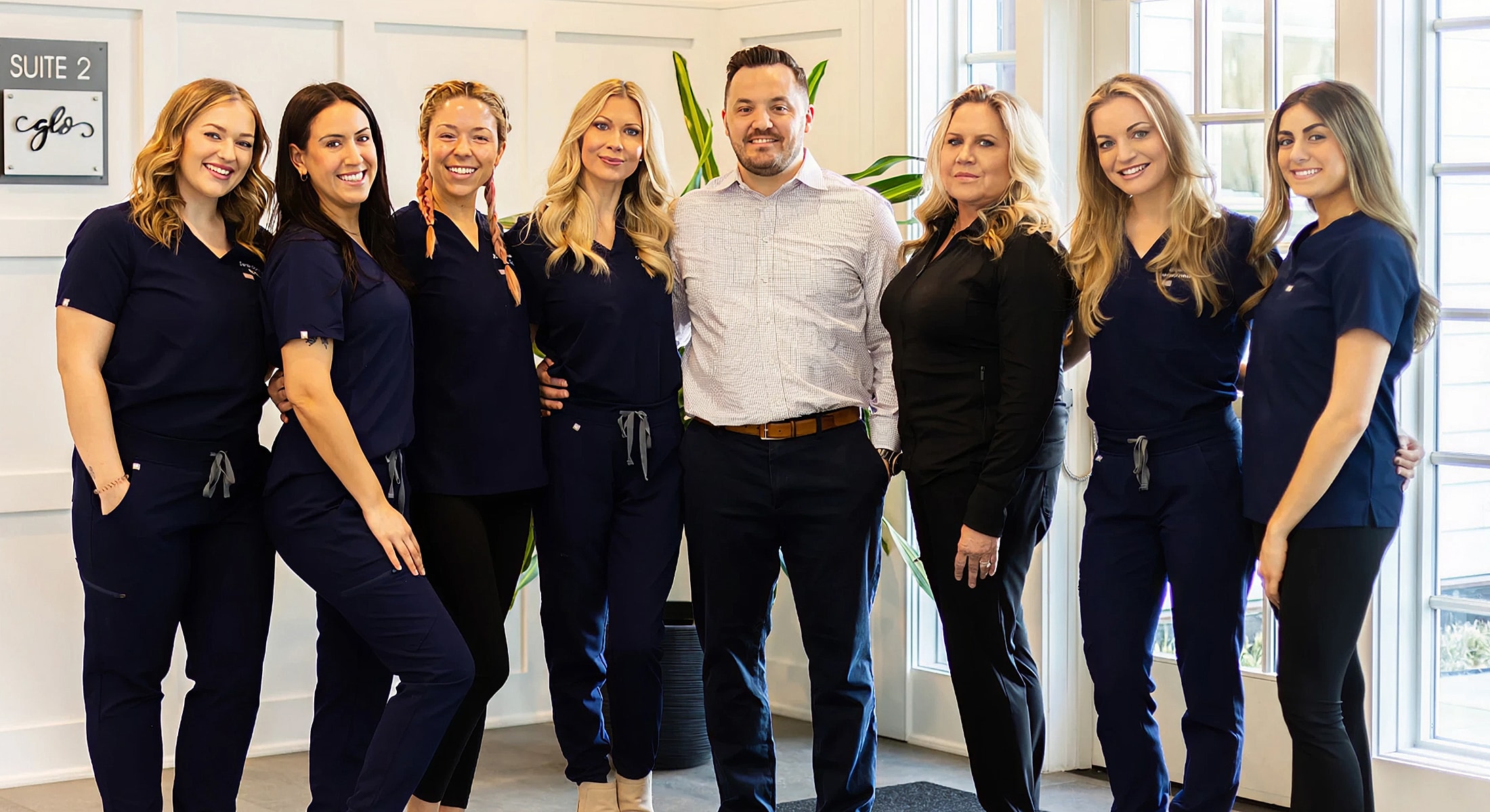 Team of professionals posing in clinic setting.