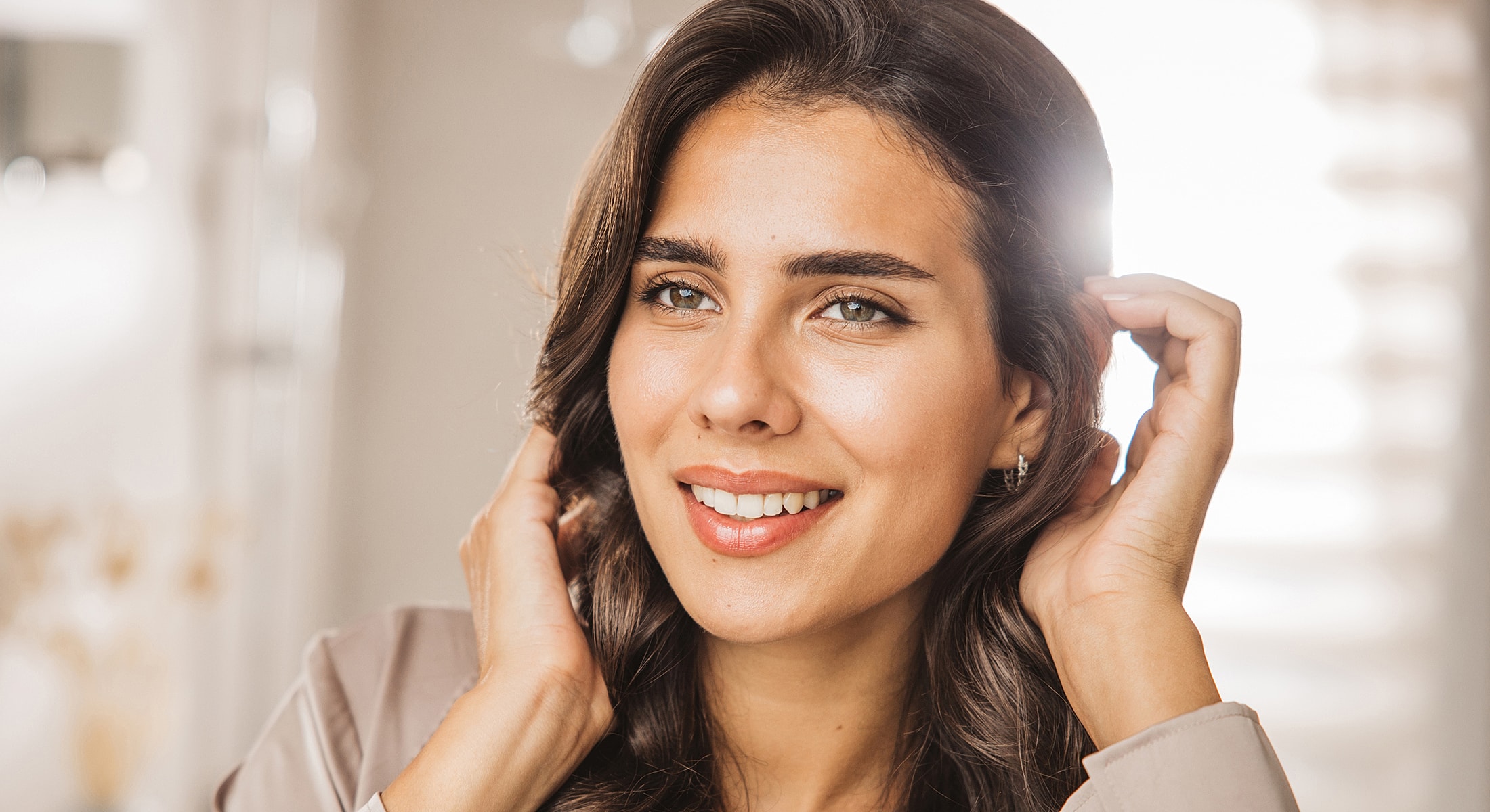 Smiling woman with wavy hair in soft lighting.